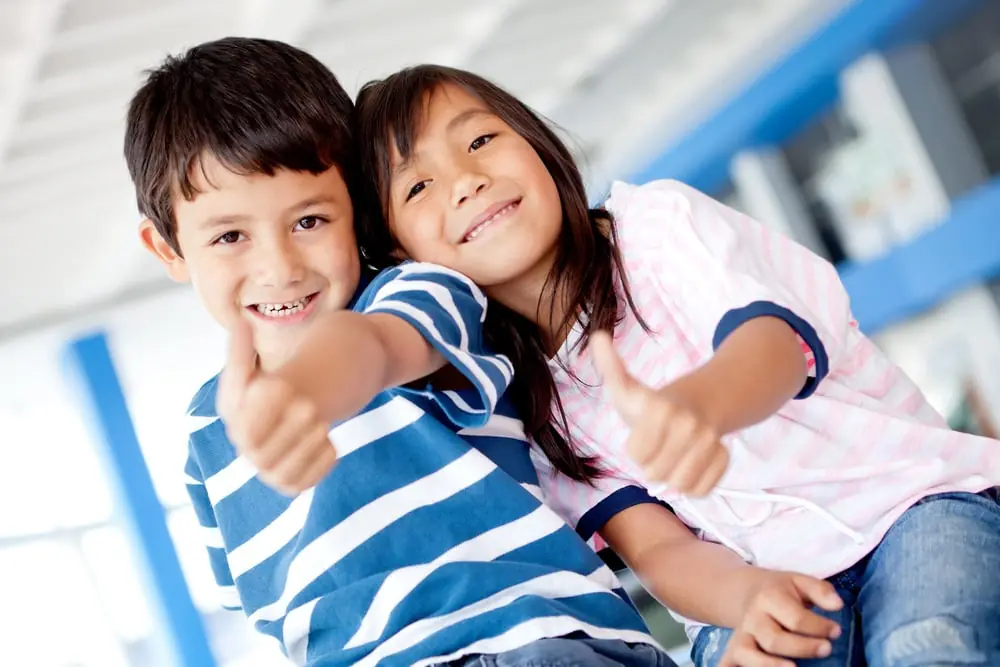 Two happy kids giving thumbs up